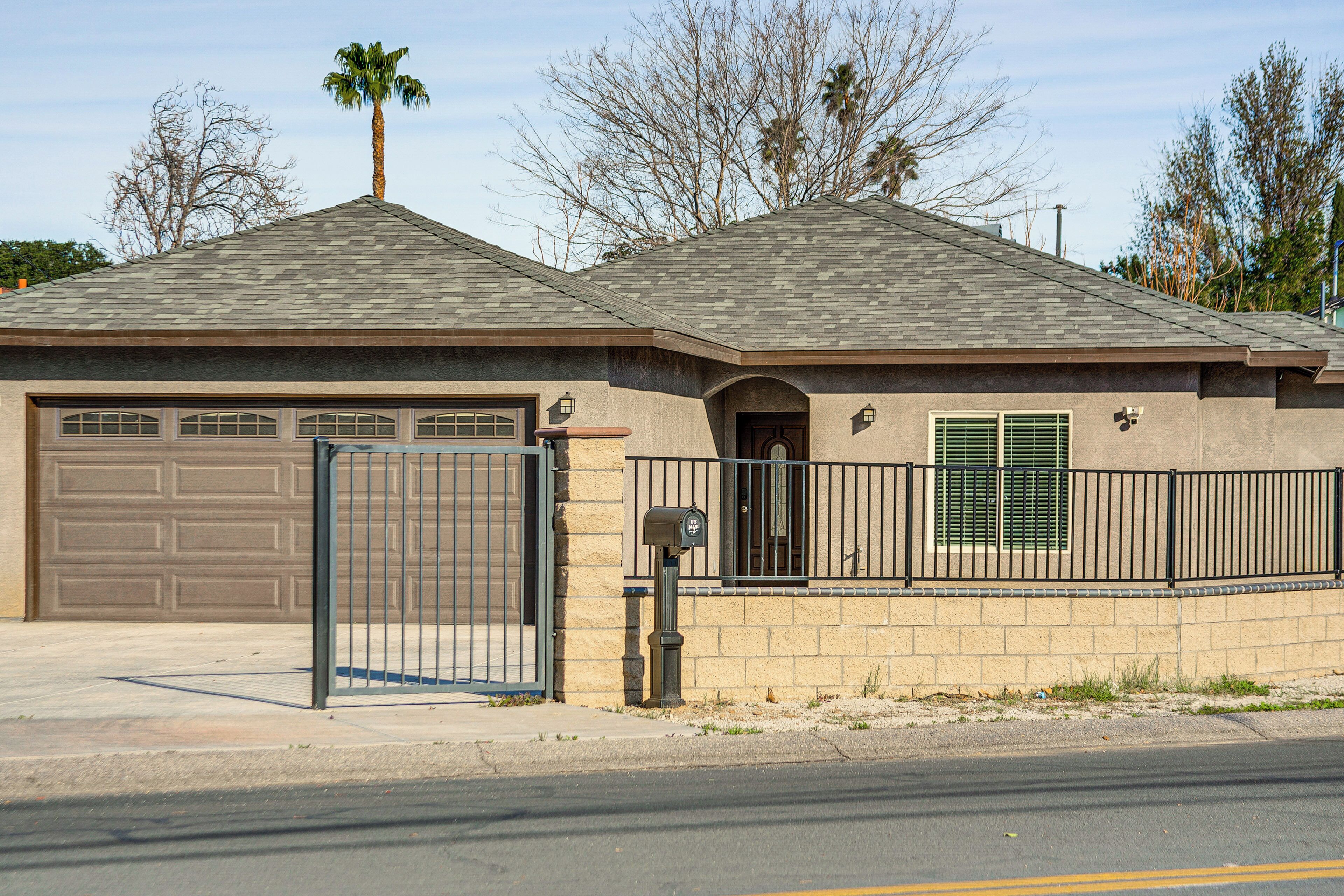 A residential house with a garage, a gated entrance, and a mailbox.