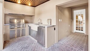 An outdoor kitchen area with a stainless steel grill, a sink, and a countertop. - Hidden Garden Retreat in the Heart of Downtown Savannah (savannah)