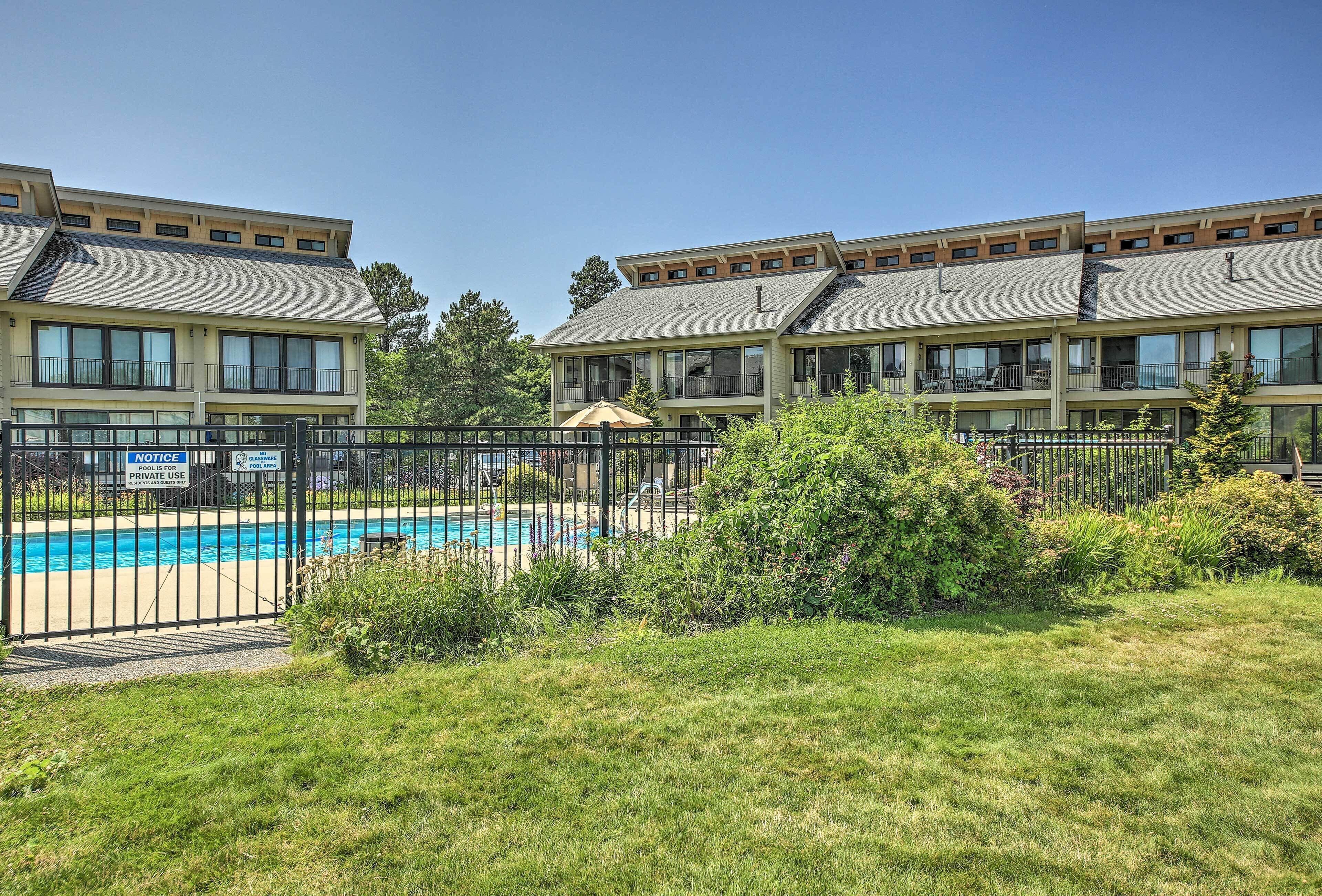 A hotel with multiple balconies, a swimming pool, and a fenced area.