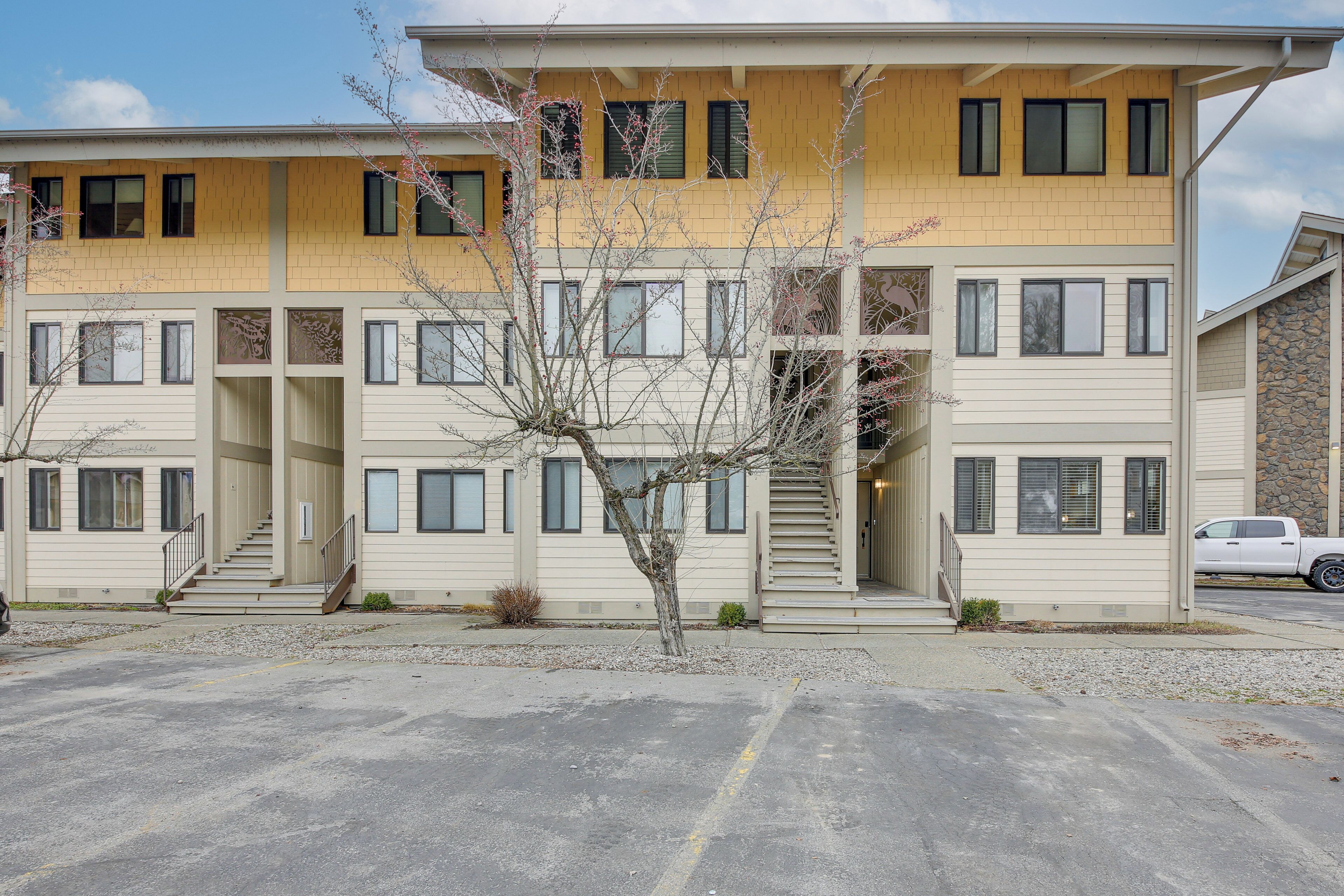 Un bâtiment à deux étages, à la façade de couleur beige, doté de nombreuses fenêtres et d’un parking situé à l’avant.