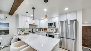 A modern kitchen with white cabinets, a large island, stainless steel appliances, and pendant lighting. - Seasonal Pool & Marina! Condo on Lake Pend Oreille (Sandpoint)