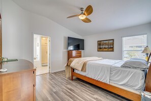 Ein Schlafzimmer mit einem hölzernen Bett, einem Deckenventilator, einem Fernseher und einem Gemälde an der Wand.