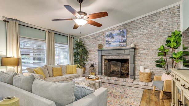 A living room with a brick fireplace, a ceiling fan, and a sofa with cushions. - 5 Mi to Historic Dtwn Beaufort: Family Gem w/ Yard (Beaufort)