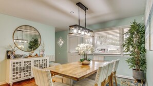 A dining area with a wooden table, striped chairs, a hanging light fixture, a potted plant, and a decorative mirror on the wall. - 5 Mi to Historic Dtwn Beaufort: Family Gem w/ Yard (Beaufort)