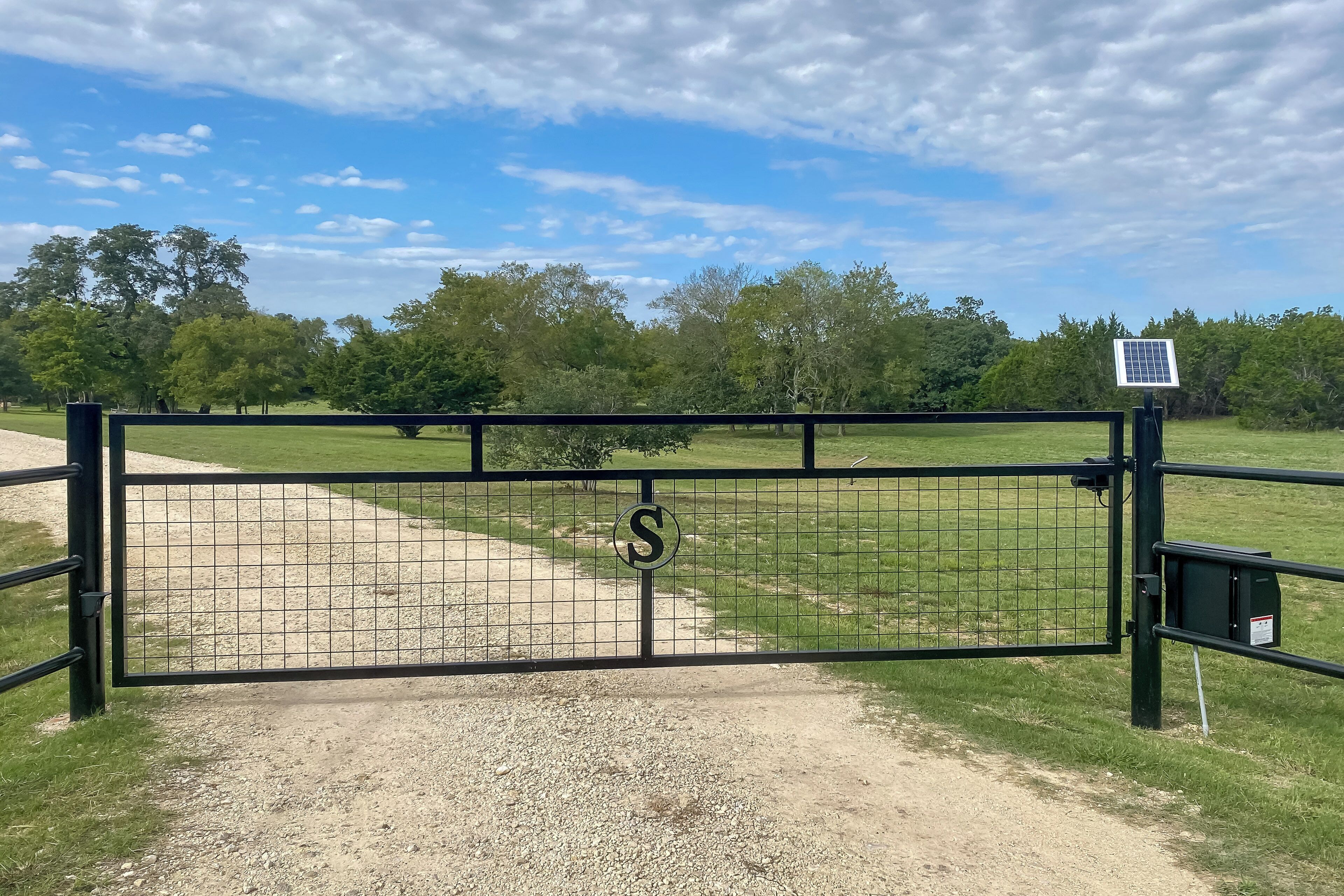 A gated entrance with a solar panel and a sign.