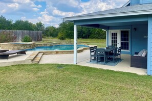 Un jardin avec une piscine, un patio couvert et un coin repas.