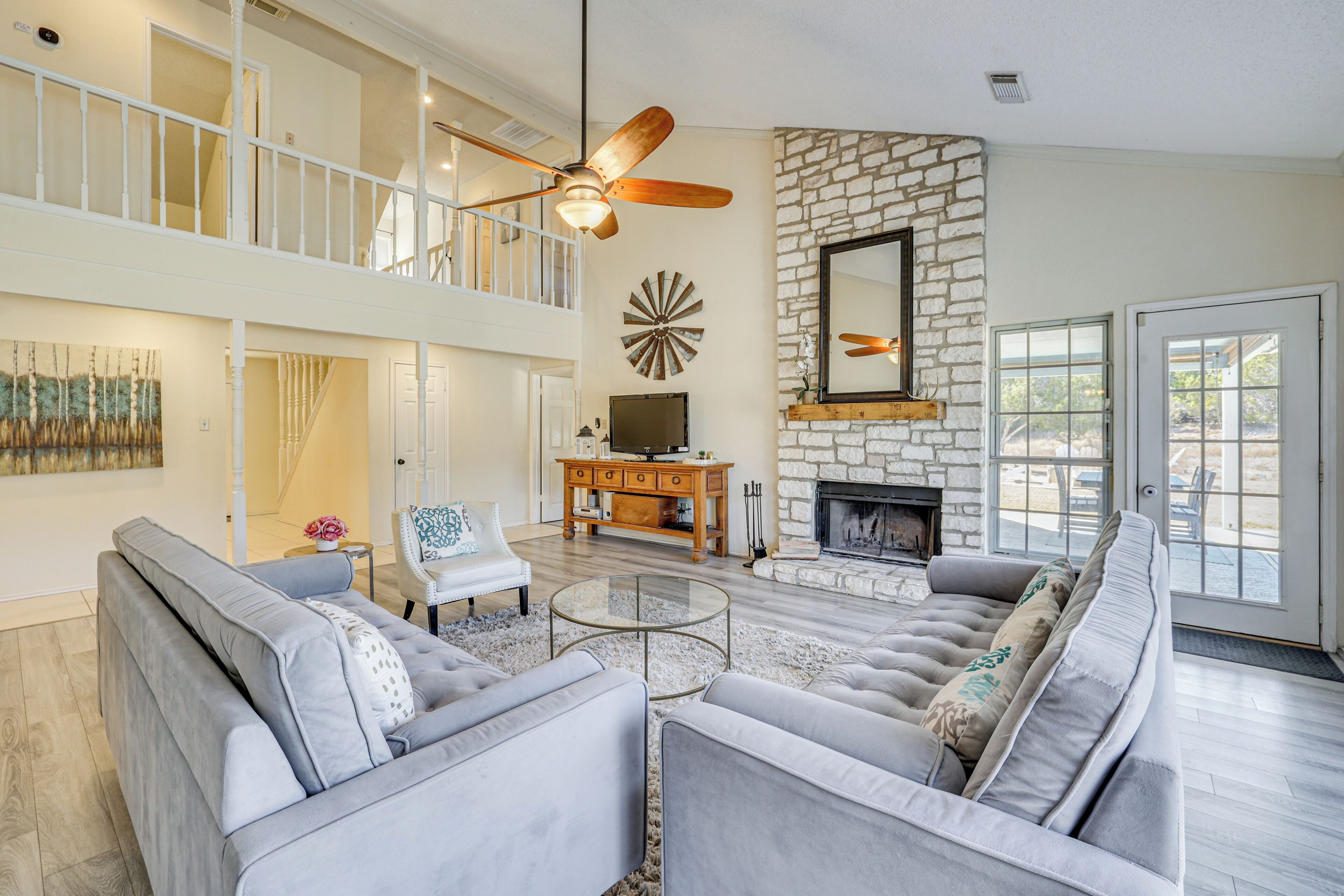 A spacious living room with a high ceiling, a fireplace, a television, and a staircase leading to an upper level.