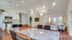 A modern kitchen with a marble countertop, stainless steel appliances, and a dining area with leather chairs. - Walk to Avondale Eats & Brews: Urban Getaway (Birmingham)