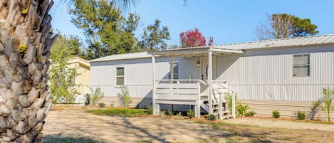 A single-story mobile home with a covered porch and a small staircase leading to the entrance.