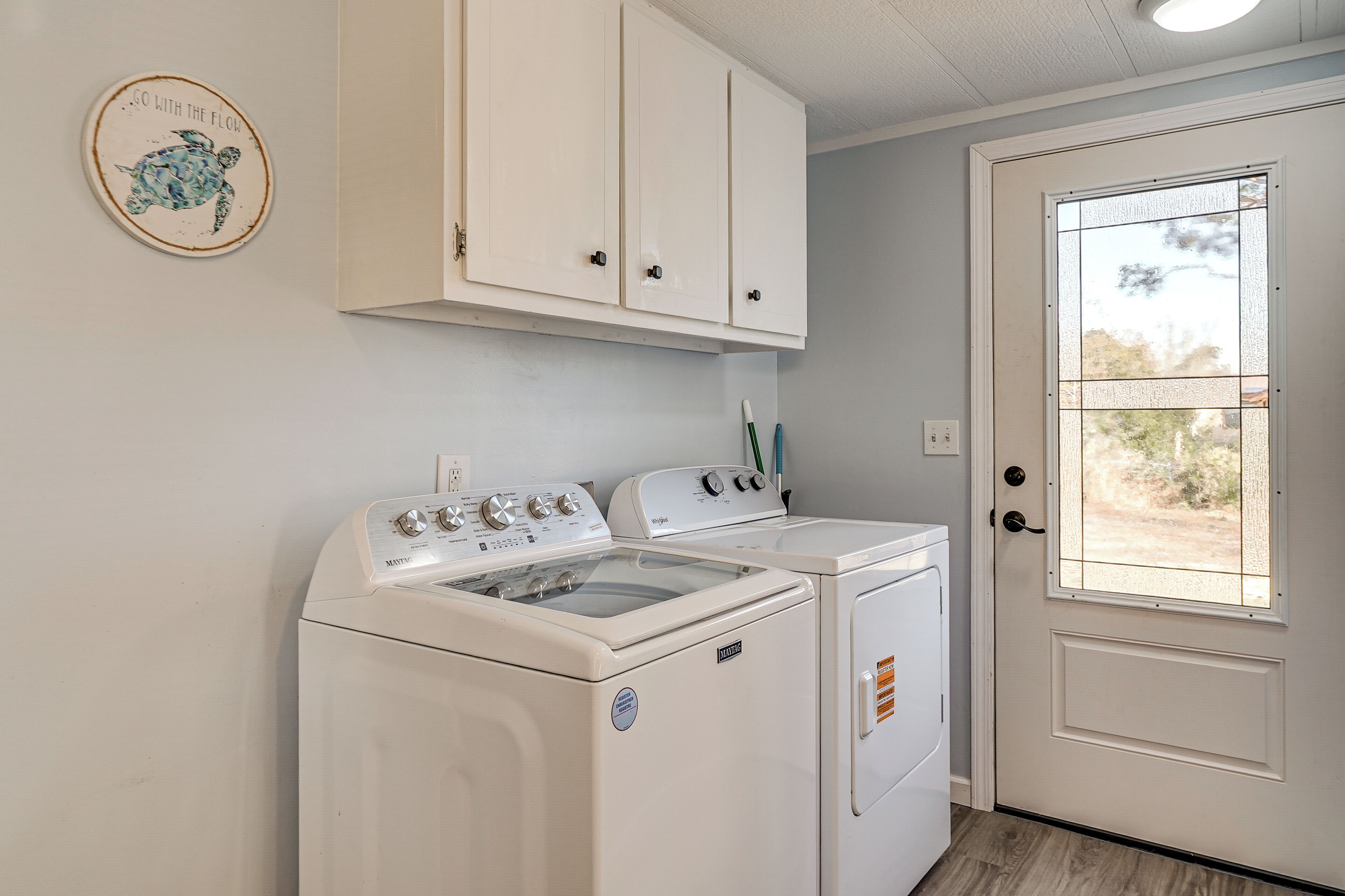 A laundry area with a washer and dryer, a door with a window, and a wall-mounted cabinet.