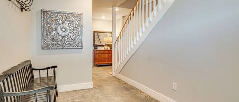 A hallway with a bench, a decorative wall piece, and a staircase.