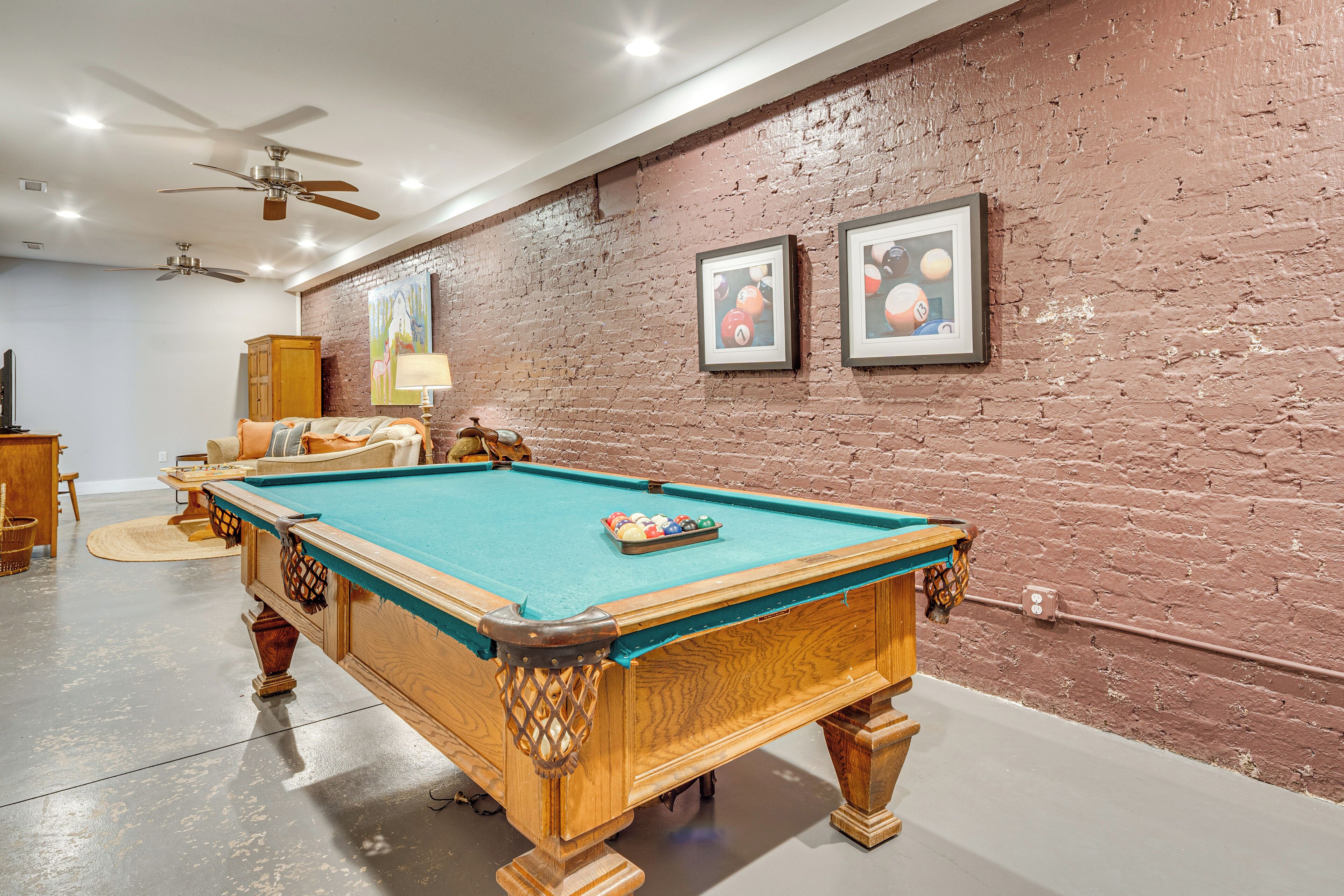 A pool table in a room with a brick wall and ceiling fans.