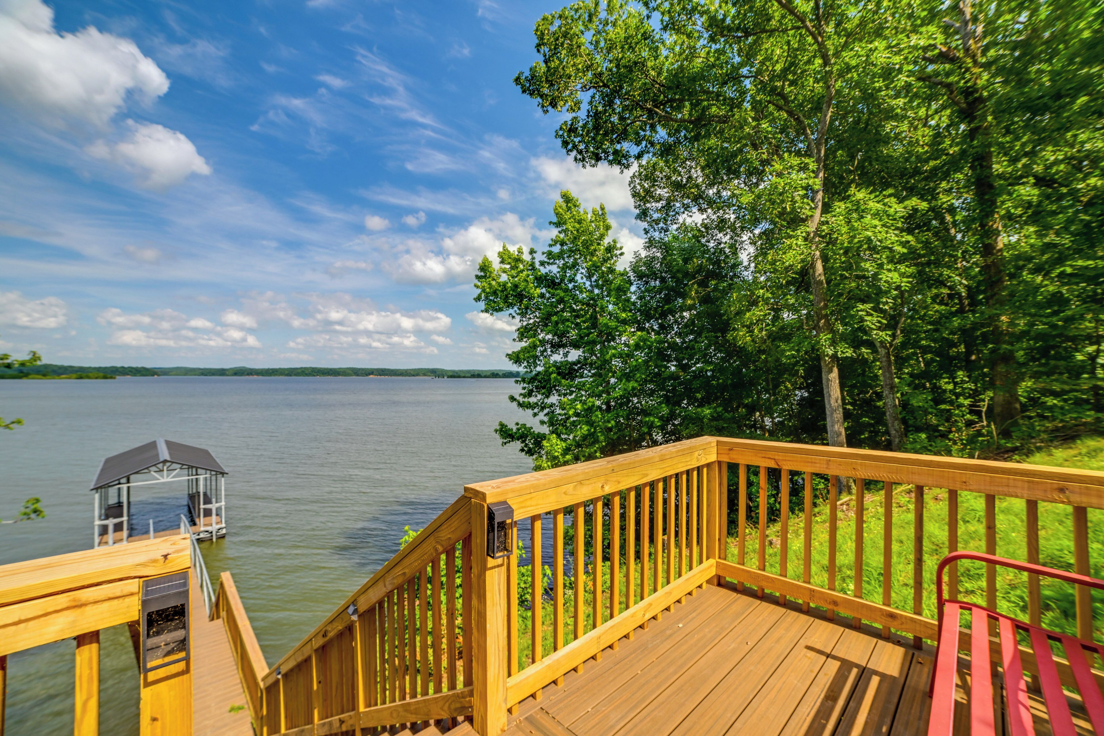 A wooden deck with a gazebo overlooking a lake, surrounded by trees.