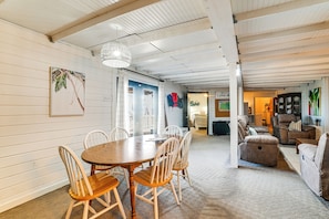 A spacious room with a wooden dining table and chairs, a comfortable sofa, and a large window. - Summer Getaway on Kentucky Lake w/ Private Dock (New Concord)