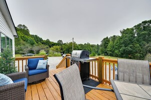 Una terraza con mobiliario exterior, una parrilla y vistas a un área boscosa.