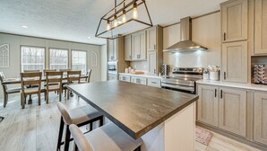 A modern kitchen with a large island, wooden cabinets, and a built-in oven. - Cozy Hillside Retreat Near Dale Hollow Lake! (Burkesville)