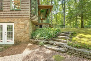 A stone house with a wooden exterior, a stone staircase leading to a porch, and a lush garden with stepping stones. - Vintage Home Nestled in the Woods of Smoky Mtns (Marble)