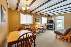 A living room with a fireplace, wooden furniture, and a stone accent wall. - Walk to Lifts! Skier's Black Mountain Base Camp (Jackson)