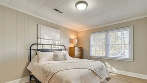 Une chambre à coucher avec un lit, une table de chevet, une lampe et une fenêtre avec des stores.