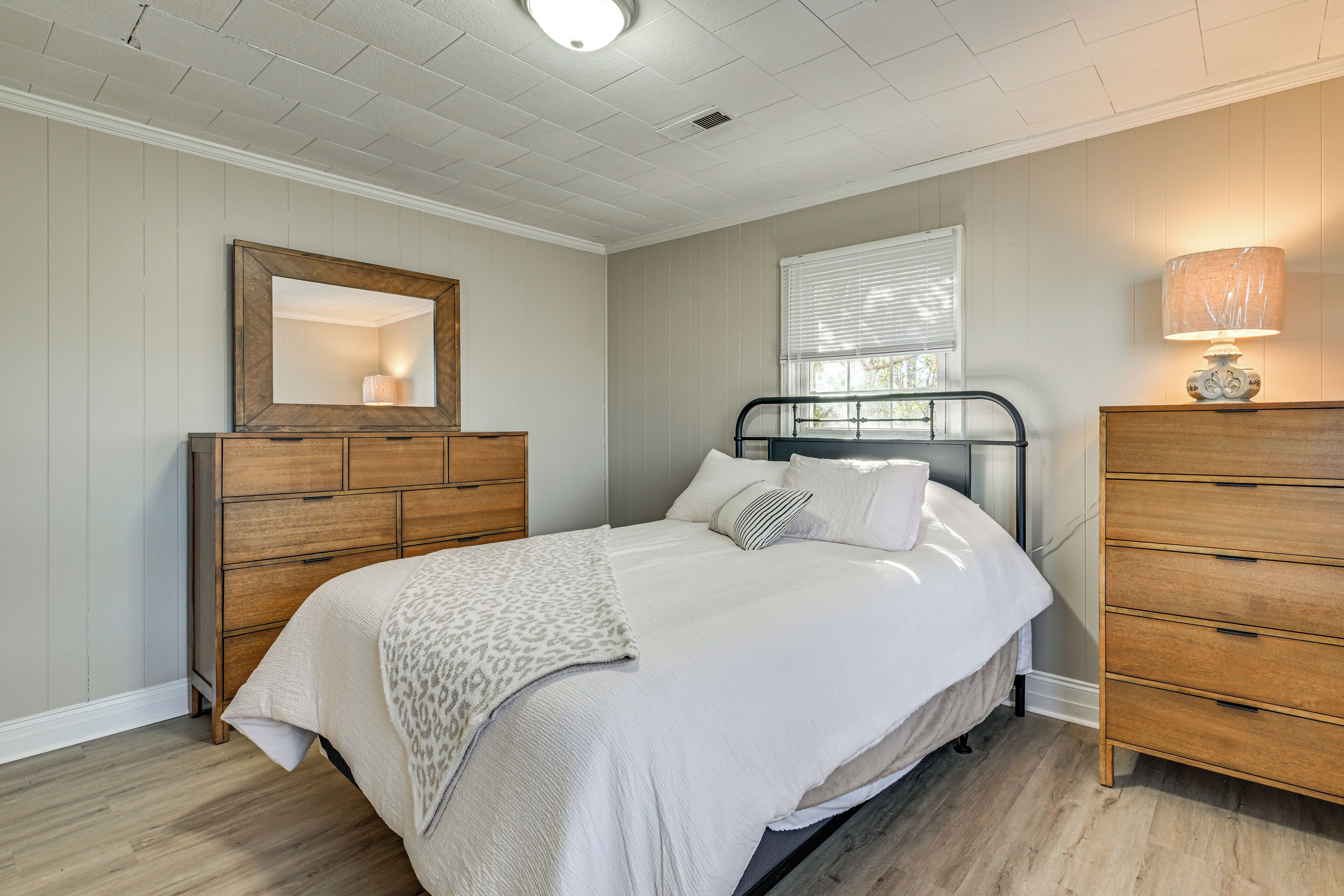 Un dormitorio con cama, cómoda y espejo.