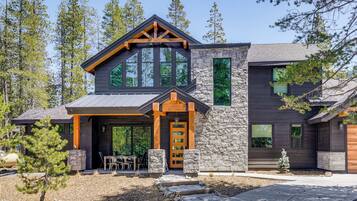 A modern house with a stone facade, large windows, and a wooden porch.