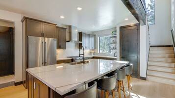 A modern kitchen with a large island, stainless steel appliances, and a view of the outdoors.