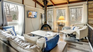 Un salon confortable avec une cheminée, un canapé, un fauteuil et un téléviseur.