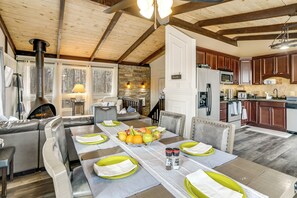 Een gezellig keuken in landhuisstijl met een stenen openhaard, houten balken en een eethoek met een lange tafel gedekt voor vier personen.