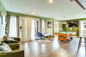 Una habitación con mesa de billar, sillas verdes, una mesita con una caja y una silla con una etiqueta.