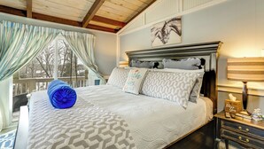 Une chambre à coucher avec un lit, une table de chevet, une lampe et une fenêtre avec des rideaux.