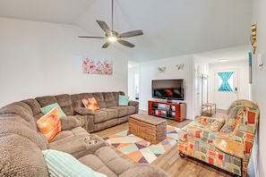 A living room with a sectional sofa, a patterned armchair, a television, and a ceiling fan. - Family Home in Fountain Inn, 2 Mi to Main St! (Fountain Inn)