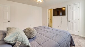 A bedroom with a bed, a ceiling fan, a door, and a wall-mounted TV. - Family Home in Fountain Inn, 2 Mi to Main St! (Fountain Inn)