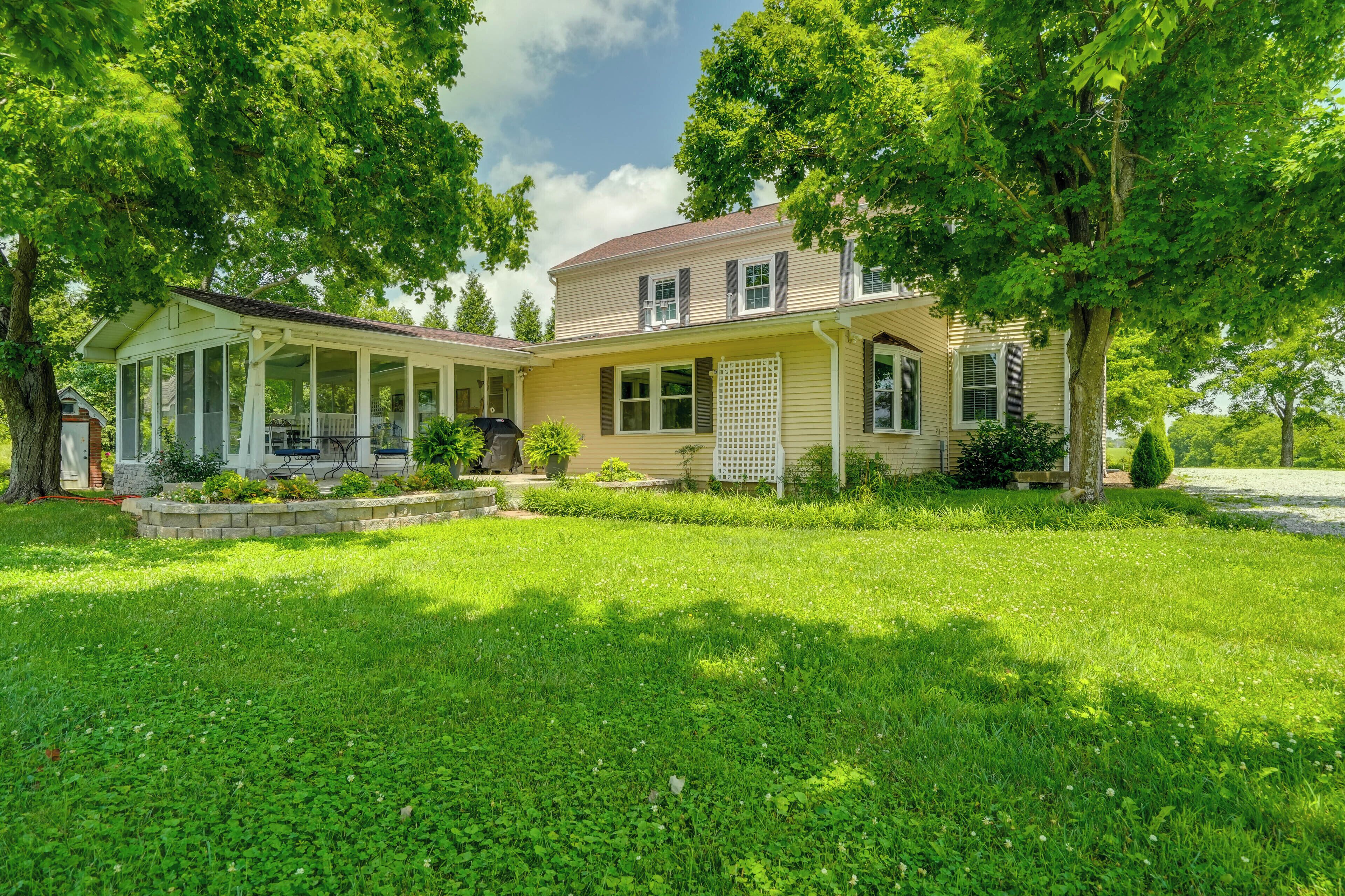 A two-story house with a covered porch, a well-maintained lawn, and mature trees.
