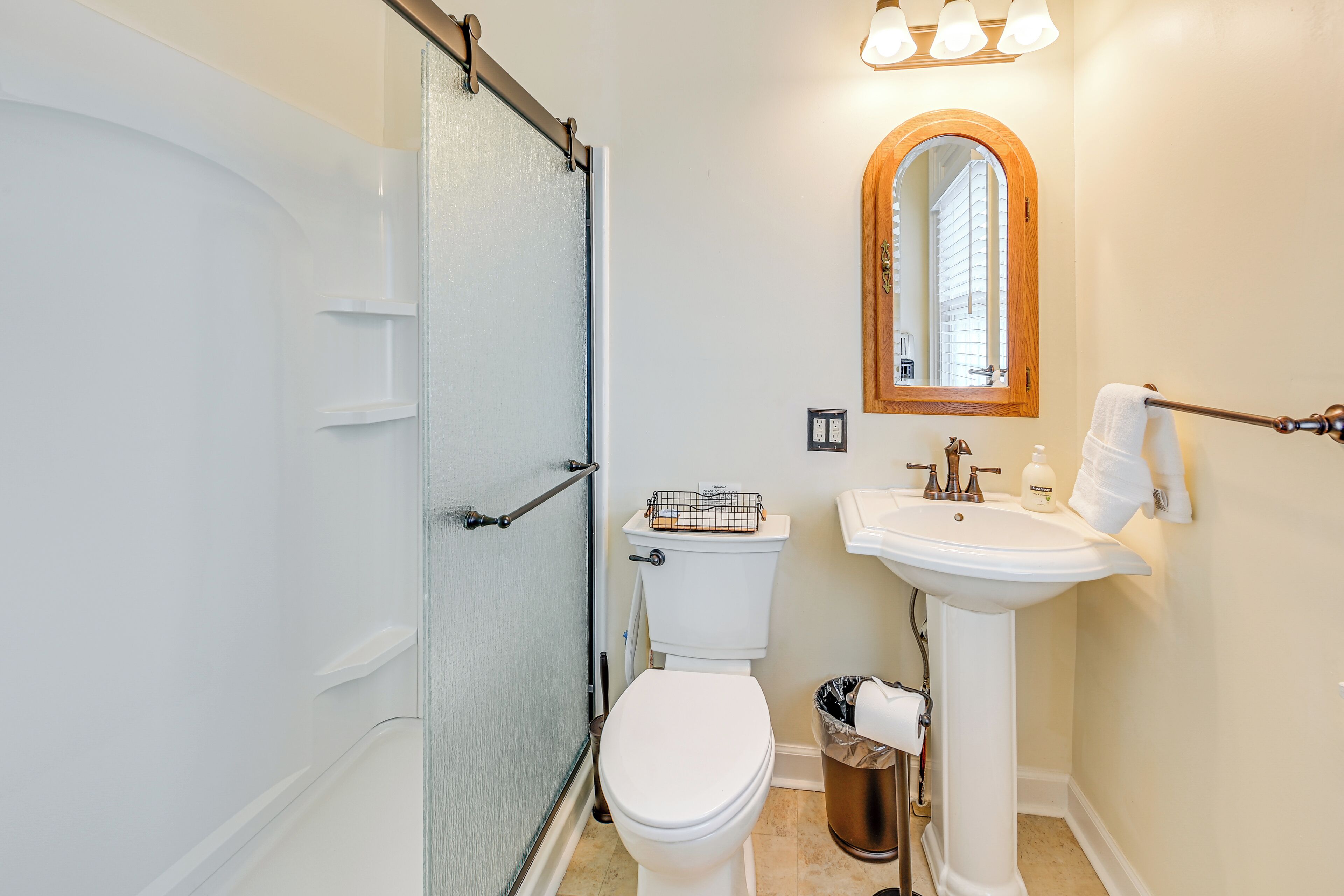 Un bagno con il water bianco, un lavabo su piedistallo, uno specchio e una tenda da doccia.