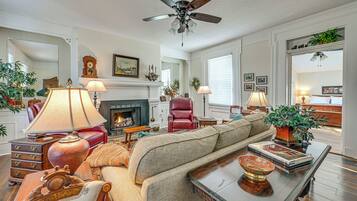 A living room with a sofa, a coffee table, a fireplace, and a ceiling fan.