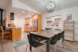 Una cocina moderna con armarios de madera, una isla central y un comedor con una mesa grande y sillas.