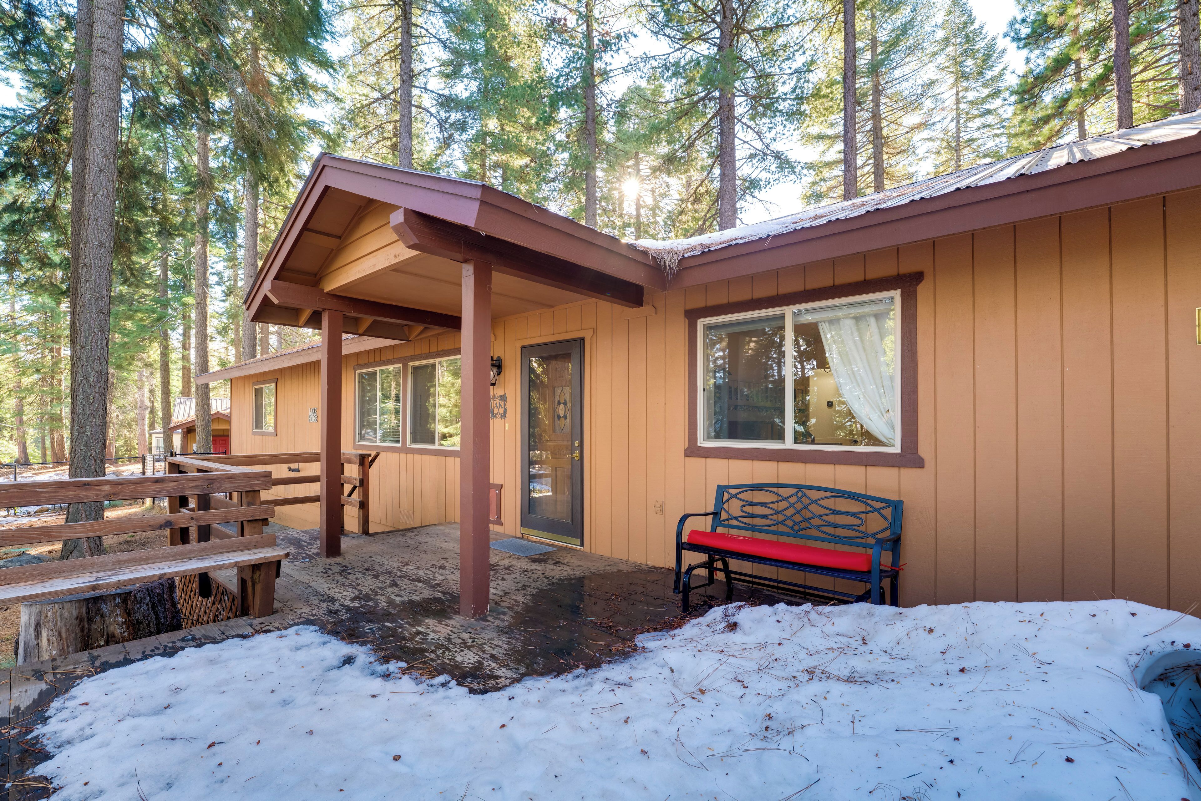 A cabin with a covered porch, a bench, and a snow-covered ground.