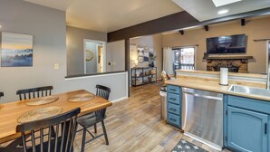 A modern kitchen with a wooden dining table, blue cabinets, and a built-in dishwasher.