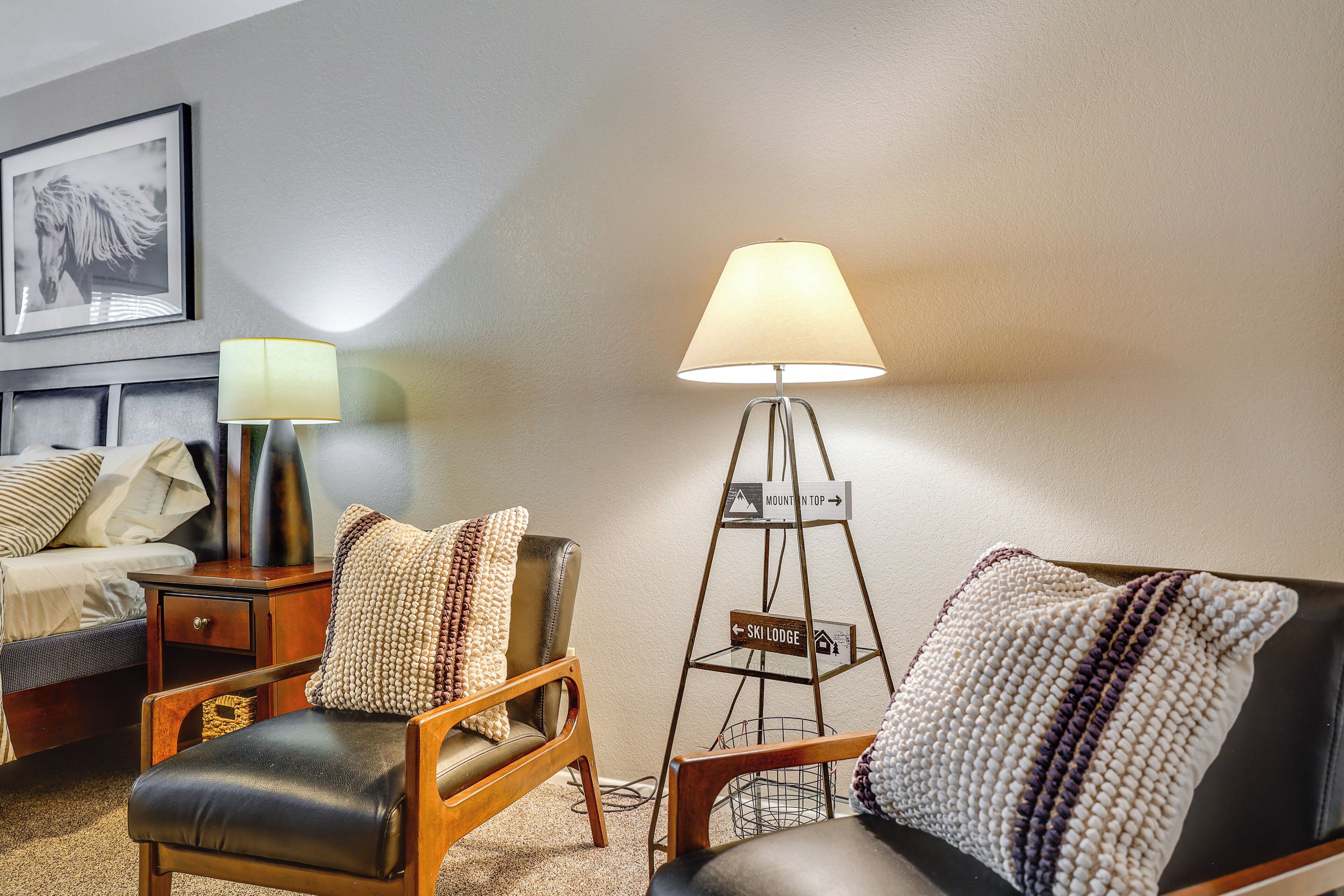 Een hotelkamer met een bed, twee fauteuils, een vloerlamp en een decoratief bord.