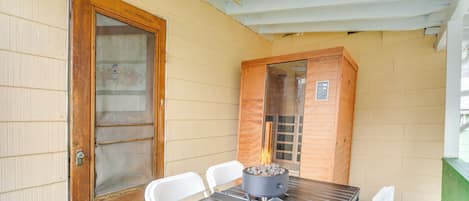 A covered patio with a table and chairs, a fire pit, and a wooden cabinet.