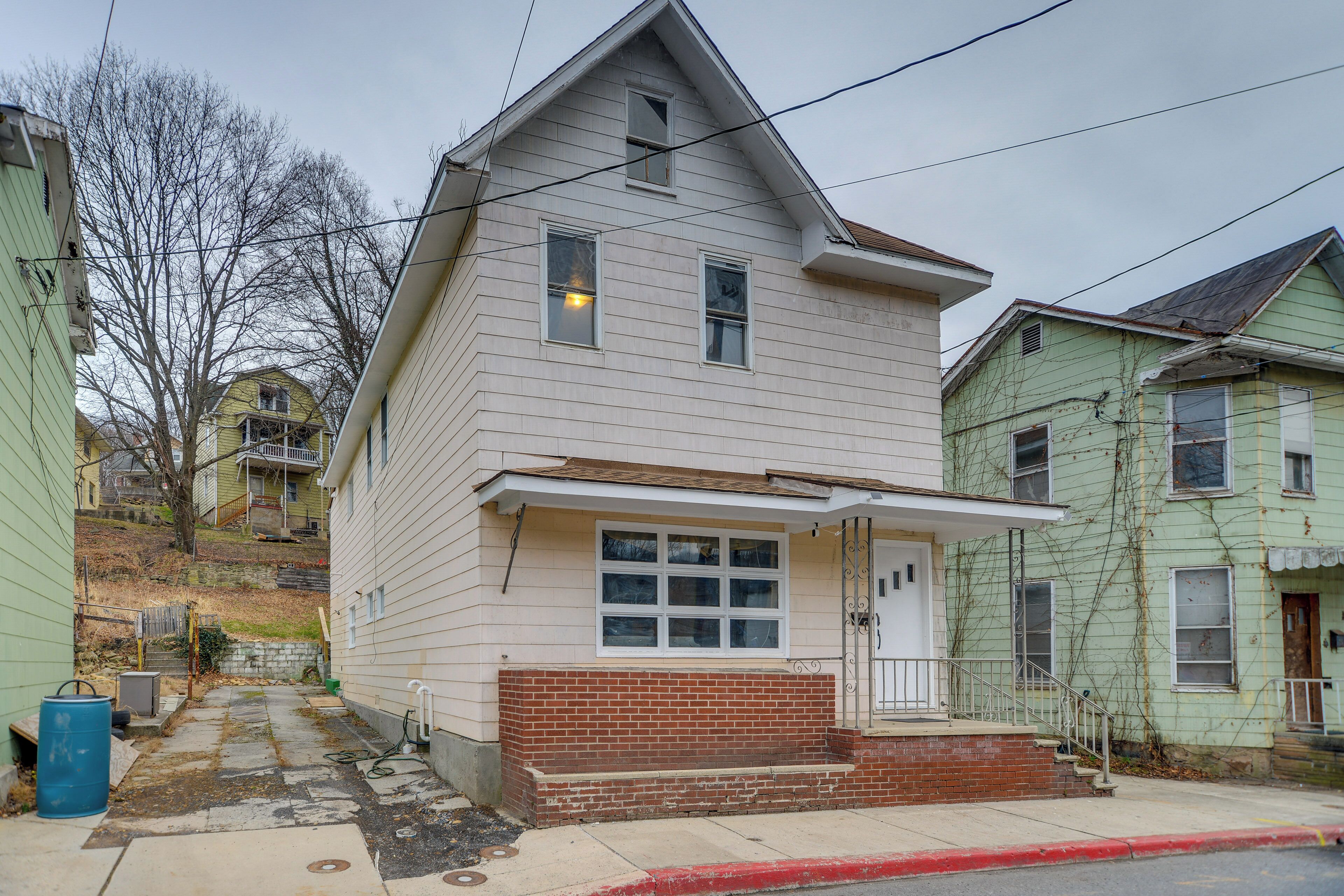 A two-story house with a front porch, a garage, and a visible driveway.