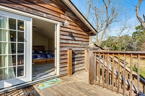 Una cabaña de madera con un cerramiento de vidrio corredera que da a un dormitorio con cama y ventana.