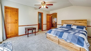 A bedroom with a wooden bed, a ceiling fan, and a door leading to another room. - Cozy Barn Apt w/ 5-acre Pond in South Georgia! (Doerun)