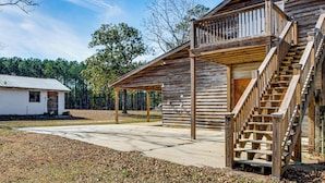 A rustic wooden cabin with a covered porch and a staircase leading to a second floor. - Cozy Barn Apt w/ 5-acre Pond in South Georgia! (Doerun)