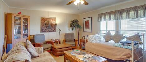 A cozy living room with a sofa, armchair, coffee table, and a bed with a canopy.