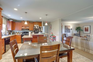 A modern kitchen with wooden cabinets, a glass dining table, and a central island. - Fishing Dock! 'oarhouse South' Near Venice Marinas (Venice)
