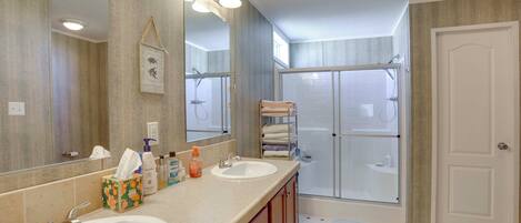 A bathroom with two sinks, a large mirror, and a shower area.