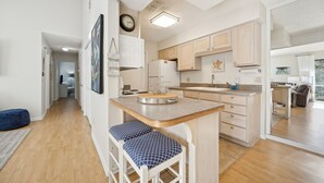 A modern kitchen with a central island, wooden cabinets, and a built-in refrigerator. - Forest Ridge U8 2 Bedroom Condo (Fernandina Beach)