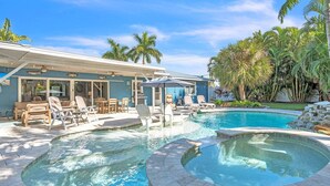 Ein Poolbereich mit zwei Whirlpools, Liegestühlen und einer überdachten Terrasse.