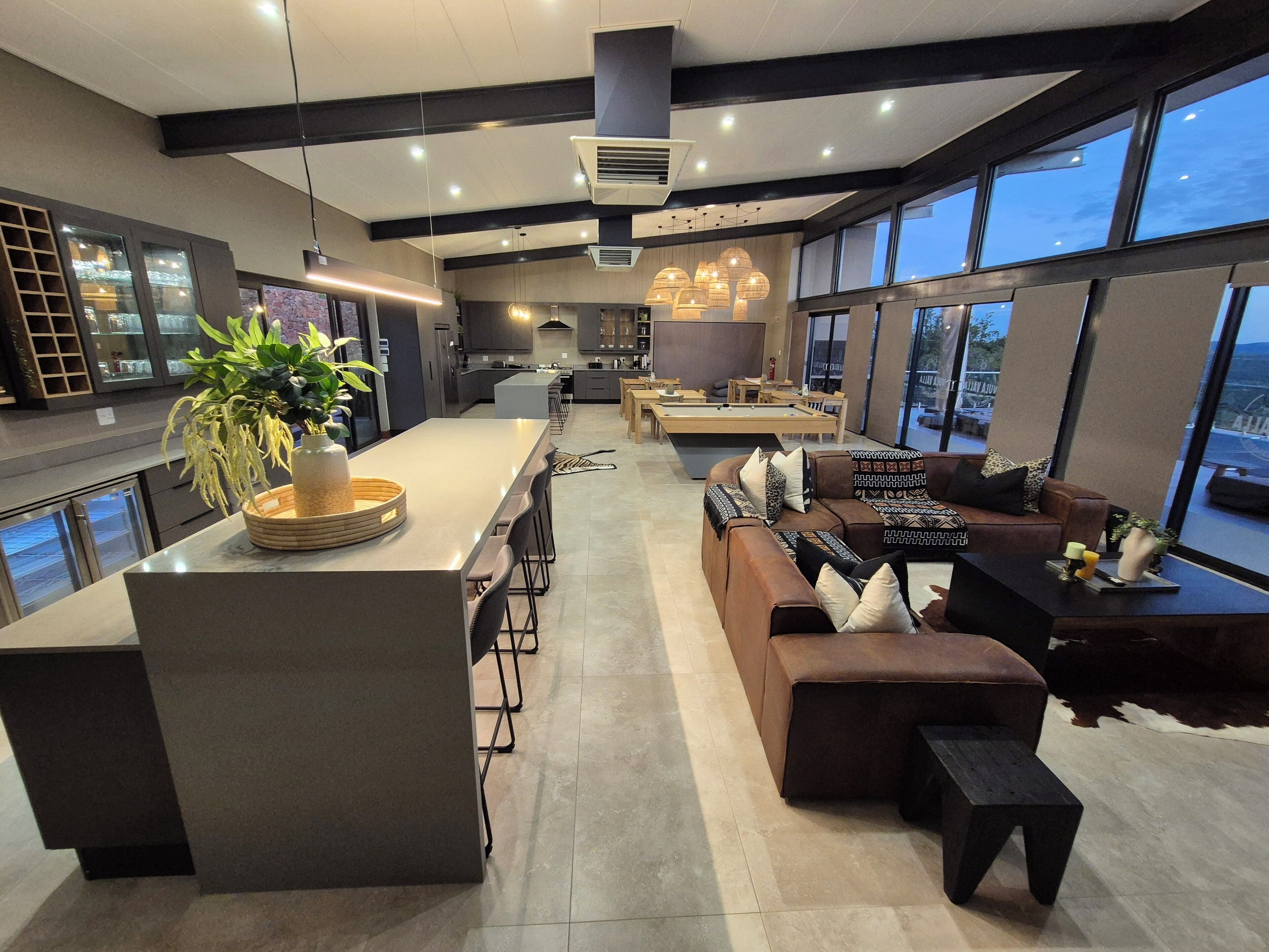 Een moderne keuken met een centraal eiland, barstoelen, een bank en een pooltafel.